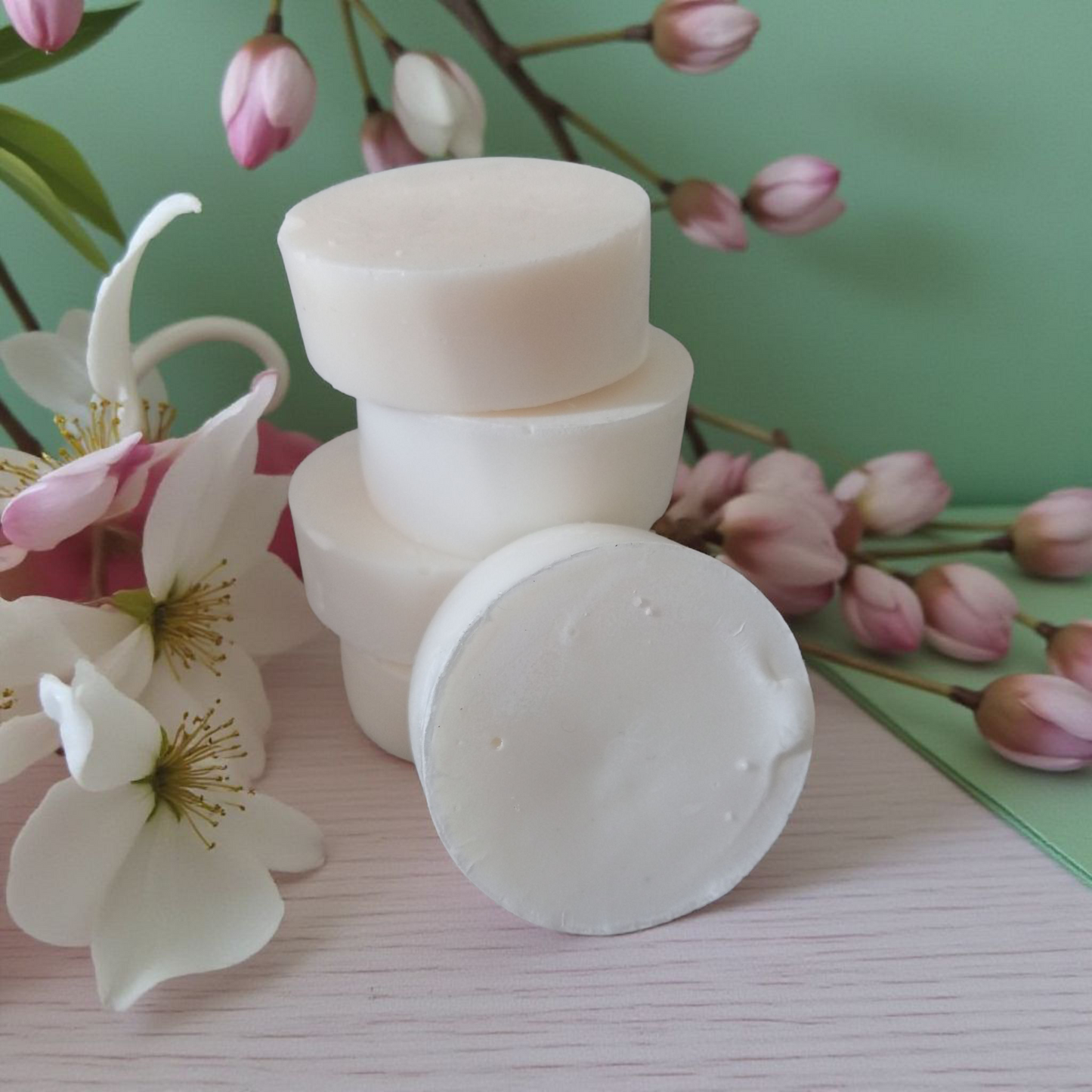 Stack of white tallow soap bars with floral elements on a light surface