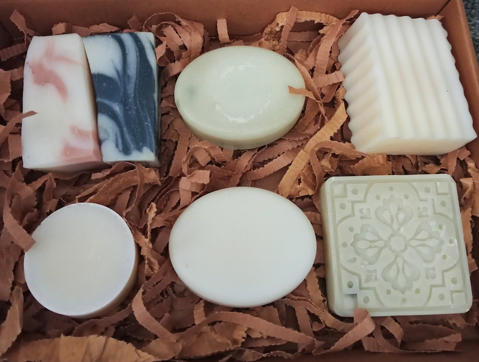 Assorted soaps in a box with brown shredded paper